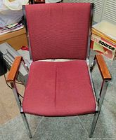 Front angled view of the maroon upholstered office guest chair showing metal frame, wooden armrests, and cushioned seat and backrest.