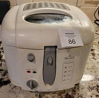 Front and top view of white Rival electric deep fryer showing dial, power and ready indicator lights, handle, and viewing window on lid.