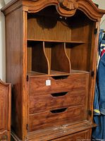 Front view of solid wood 5-drawer armoire showing three upper drawers, two bottom drawers with metal hardware, and open shelf space with removed doors.