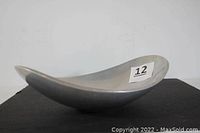 Side angle of oval aluminum alloy bowl showing modernist curved shape and matte finish.