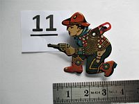 Front view of vintage tin cowboy toy with ruler showing size