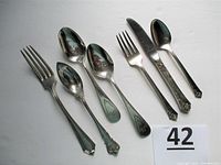 Full overview of seven sterling silver flatware pieces: forks, spoons, knife with various patterns and sizes including children's flatware.