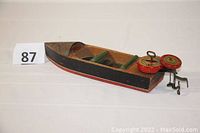 Full side view of the wooden toy boat showing the hull and attached outboard motor.
