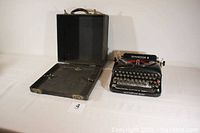 Remington Model 5 typewriter next to its open original carrying case, laid flat showing interior.