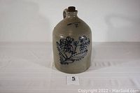 Overall view of the stoneware jug showing handle, spout, stopper and floral decoration