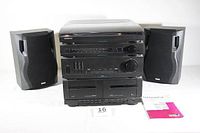 Front view of the entire Magnavox sound system including the turntable on top, two black RCA RS1285 speakers on each side, amplifier, tuner, and cassette deck with accompanying manuals.