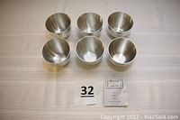 Top and side view of 6 polished pewter cups arranged in two rows of three. Includes identification cards with '32' and pamphlet showing 'Pewter Garden' marking.