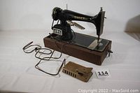 Front and side view of the black Singer sewing machine with attached cords and foot pedal, showing the brand name on the machine arm and the motor unit.