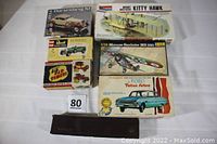 All six vintage model kit boxes displayed in a single image. Packaging shows various automobile and airplane models including Ford Falcon, Duesenberg SJ, Morane Saulnier MS 230 airplane, Wright Brothers Kitty Hawk biplane, LiLl Old Timers Mercer Raceabout box, and Revel Quick Construction Kit Bentley.