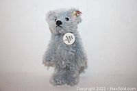 Light blue jointed teddy bear with Steiff tag and button on ear shown against white background.