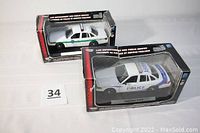 Two MotorMax 1:24 scale police cars in original boxes, both white Ford Crown Victoria models with Police markings, visible box wear.
