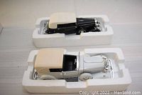 Both 1/32 scale Cadillac models in original boxes, showing black Fleetwood and silver Town Car models side by side in white styrofoam packaging.