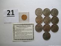 1999 gold-plated Susan B. Anthony Dollar in protective casing alongside ten 1976 Eisenhower Bicentennial Dollars, all with some wear. Certificate of Authenticity included.