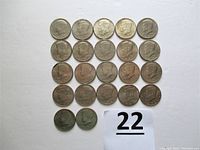 Top-down view of 22 Kennedy Half Dollar coins arranged in rows showing obverse side with portraits of JFK.