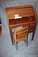 Photo of vintage maple roll top desk closed with chair in front.