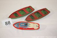 Three vintage boats including one detailed Lindstrom wind-up speedboat and two smaller flat steel boats in red and green.