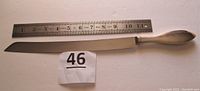 Full length view of knife next to ruler showing total length of 16 inches and an 11 inch blade.