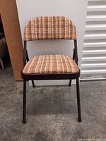 Front view of one folding chair showing cushioned striped seat and back with brown metal frame.