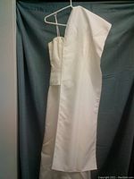Front and side view of the white evening gown hanging showing smooth satin-like finish and attached shawl.