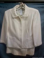 Full front view of ivory women's jacket with collar and pockets hung on a hanger.