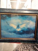 Framed artwork displaying an eagle flying over a cloud-filled blue sky.