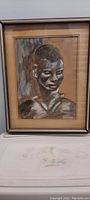 Framed portrait drawing of a man in charcoal and white chalk on brown paper.
