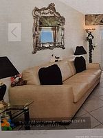 Queen size beige leather sleeper sofa shown in living room with decorative mirror and lamps.