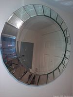 Photo showing the full round mirror with visible faceted glass border and reflection of surrounding room.