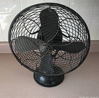 Front view of the black metal fan with four blades and GE logo on the grille, showing overall design and condition.
