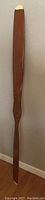 Full view of large carved wooden airplane propeller leaning against wall, showing overall size and shape.