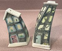 Front view of the salt and pepper house-shaped pottery shakers showing painted details and slanted shapes.