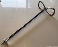 Full length view of the walking stick with leather handle and metal base spike.