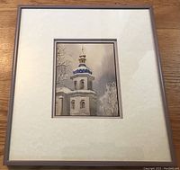 Photo showing the complete framed watercolour artwork of the church spire with double matting and wood frame on a wooden surface.