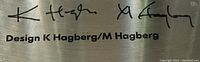 Close-up photo of the signature and design credit 'K Hagberg' and 'M Hagberg' on a label affixed to the candelabra.