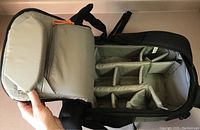 Top view of the interior showing multiple padded adjustable compartments with beige lining and orange pull tabs inside the backpack.