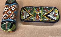 Photo of vibrant hand painted ceramic butter dish and separate lid showing colorful floral and geometric patterns.