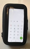 Front view of black waterproof cellphone case with clear front window showing a phone screen with calculator app.