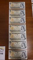 Seven 1973 Bank of Canada one dollar bills placed vertically in a line, showing the front side with Queen Elizabeth II portrait and bilingual text.