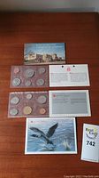 Two uncirculated coin sets from the Royal Canadian Mint from 1974 and 1989 displayed on a wooden surface, showing both coin holders and informational cards.