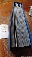Top view of a blue binder tightly packed with sleeves of first day covers, showing the thickness and quantity in the book.