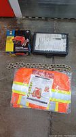 Heavy duty chain, black socket and bit set case, and orange safety vest in packaging