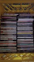 Photo showing stacks of about 48 jewel case music CDs arranged in a yellow crate.