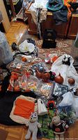 Wide photo showing assorted Halloween decor including fabric ghosts, orange pumpkins, a black metal haunted house, various small items like pumpkin carving tools, lights, and candles.