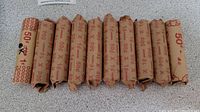 Ten rolls of pennies wrapped in red print paper showing "50¢" markings.