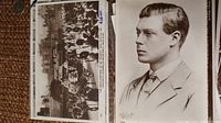 Top view of two vintage black and white postcards; one shows a royal procession with horse drawn carriages and crowd, the other is a formal portrait of a young man, likely a member of the royal family