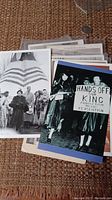 Photo showing multiple postcards stacked with a visible protest postcard and a vintage group photo postcard