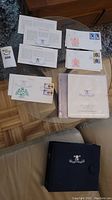 Photo showing multiple first day covers with decorated envelopes and stamps, protective sleeves and storage book.