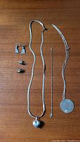 Full lot photo showing four different types of jewelry items laid out on a wooden surface