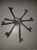 Top down view of 8 old metal keys attached to a key ring, showing overall condition and rusted patina.
