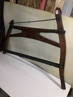 Full view of the antique bow saw showing wooden frame, tensioning rod, and saw blade